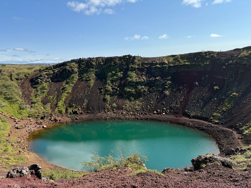 Vibrant view of Kerid Crater Lake in Iceland with lush green slopes and blue sky.