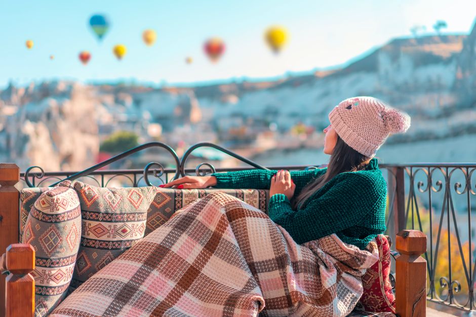 Woman relaxing in Cappadocia with hot air balloons in a scenic view.