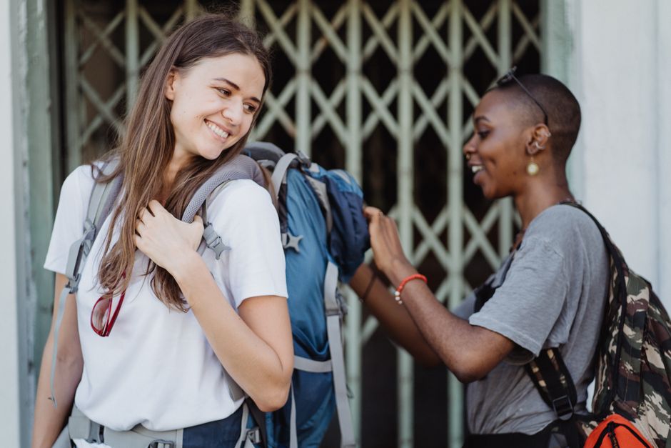 Two women smiling and enjoying a travel adventure while backpacking outdoors.