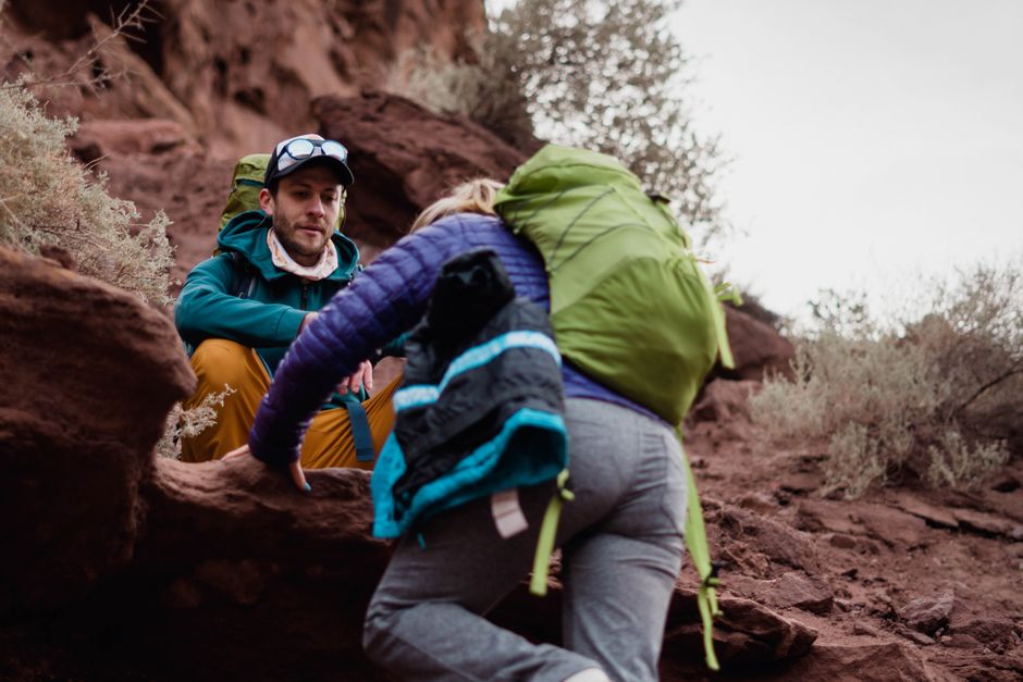 A couple enjoys rock climbing and hiking in a scenic desert landscape during daytime.