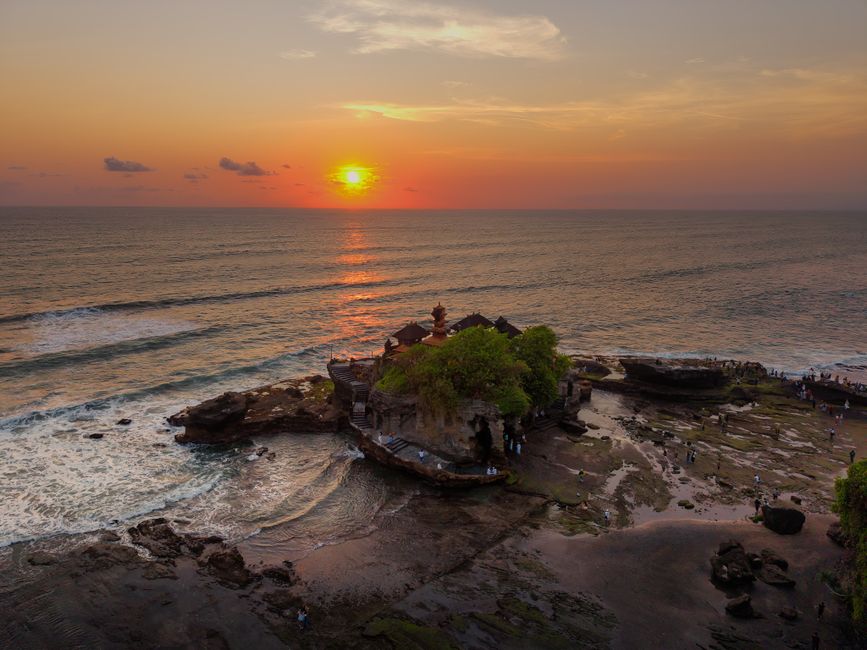 Stunning sunset view over Tanah Lot Temple in Bali with ocean and vibrant sky.