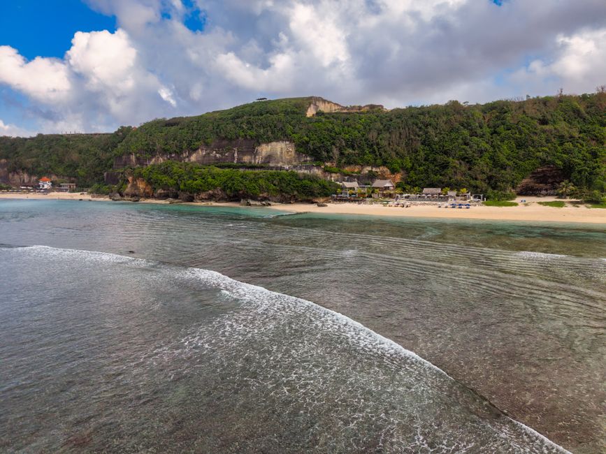 Idyllic beach with cliffs and lush greenery in Bali, Indonesia.