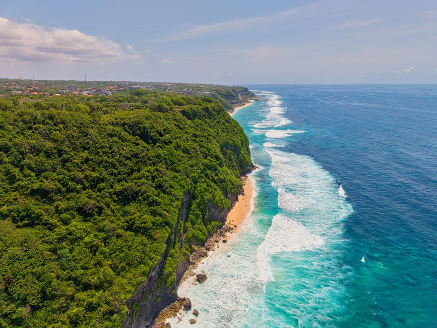 Stunning aerial shot of Uluwatu cliffs and ocean waves in Bali, Indonesia.