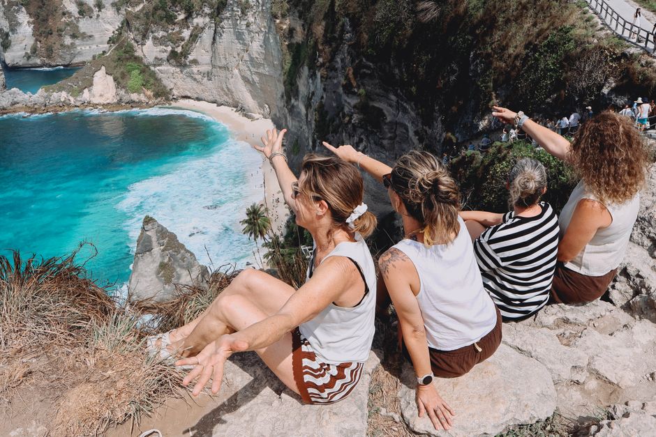A group of women sitting on a cliff enjoying the breathtaking view of Nusa Penida, Bali.