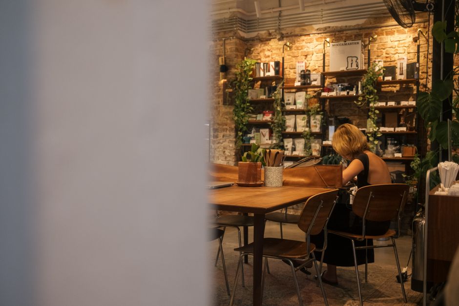 A cozy cafe interior with a woman reading at a table surrounded by rustic decor.