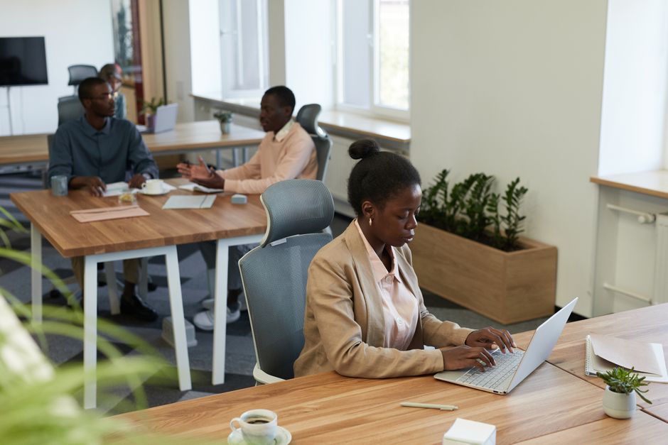 Diverse group of professionals collaborating in a modern office setting with laptops and discussions.