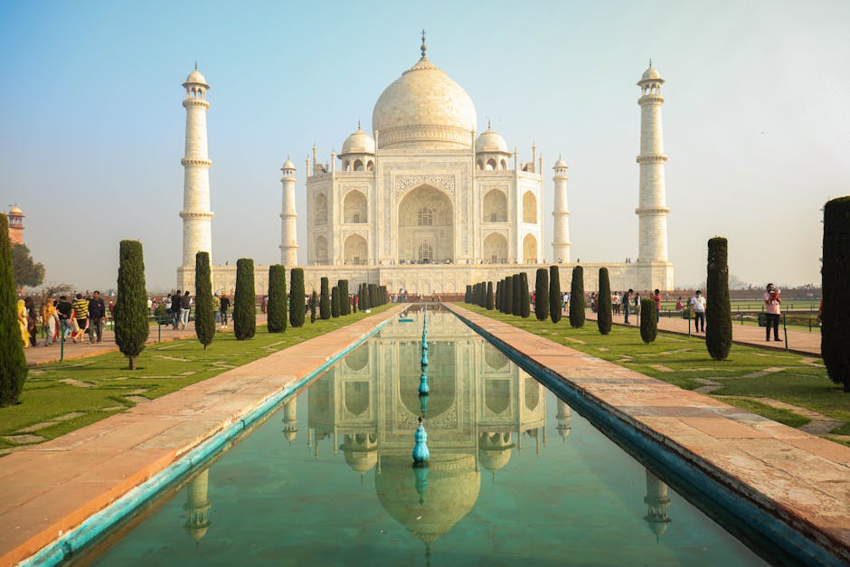 The iconic Taj Mahal stands majestically with its reflection in a serene pond, surrounded by lush gardens.