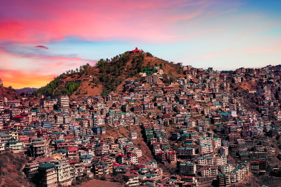 Majestic aerial view of Shimla, India with colorful buildings against a vibrant sunset sky.