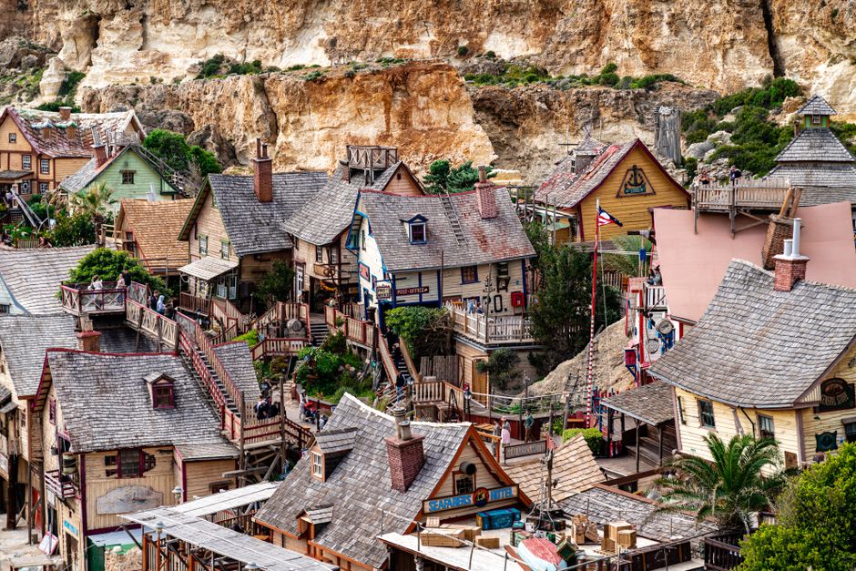 Charming village with wooden houses set against rocky cliffs in Malta, perfect for adventure seekers.