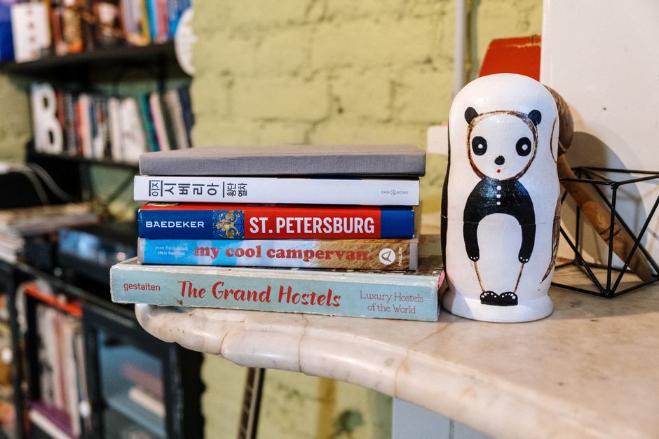 A stack of travel-themed books next to a panda-shaped decoration on a marble table.