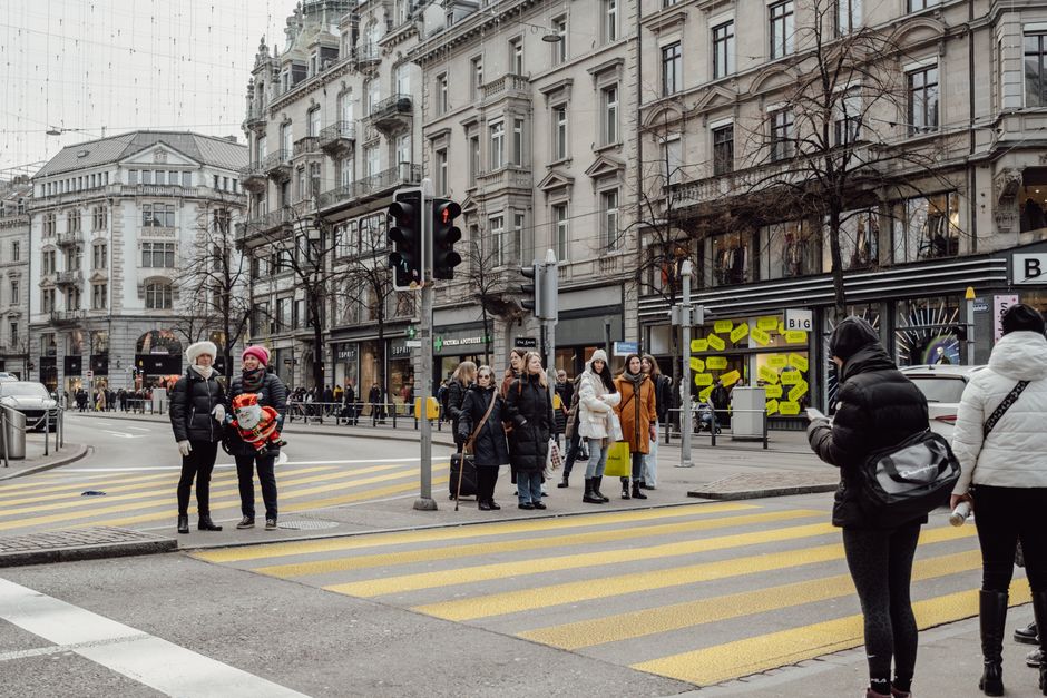 Pedestrians wait at a busy street crossing in Zurich, Switzerland during winter.