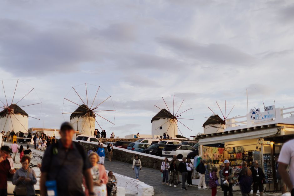 Vibrant crowds gather at the famous windmills of Mykonos, Greece, capturing the essence of Greek island life.