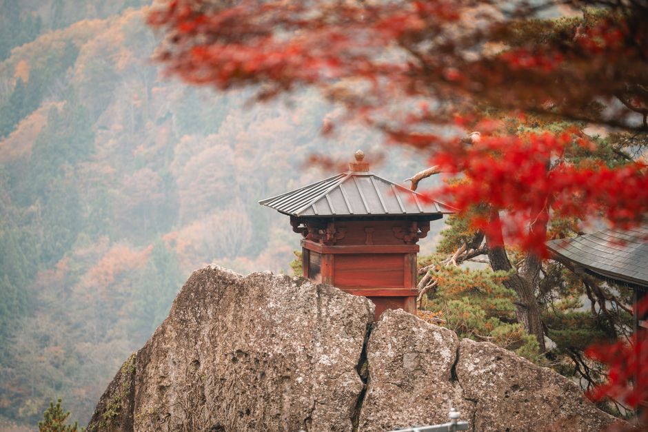 Japanese temple on a rock amid autumn foliage
