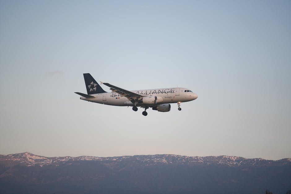 Airbus A320 aircraft descending over Geneva with a picturesque mountain backdrop at sunrise.