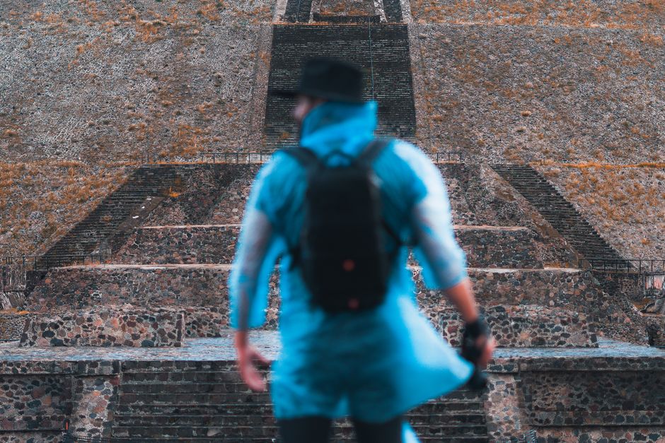 A photographer with a backpack and camera stands before the Pyramid of the Sun in Teotihuacan, Mexico.