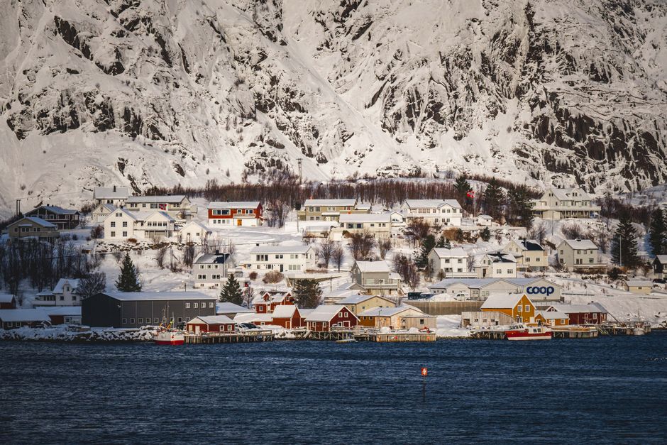 A picturesque snowy village by the water in Norway, with colorful wooden houses.