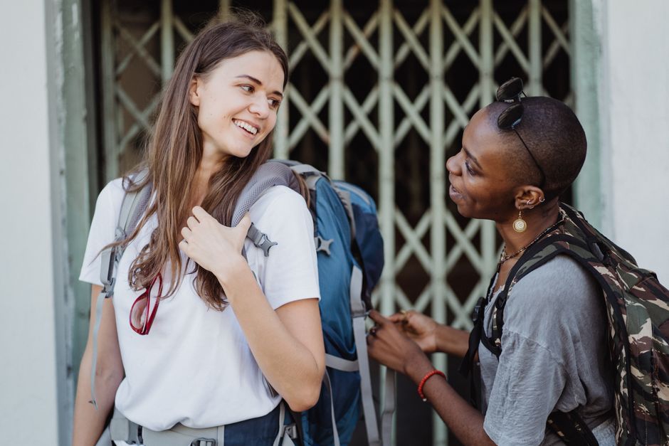 Two women travelers with backpacks sharing a moment in an urban setting.