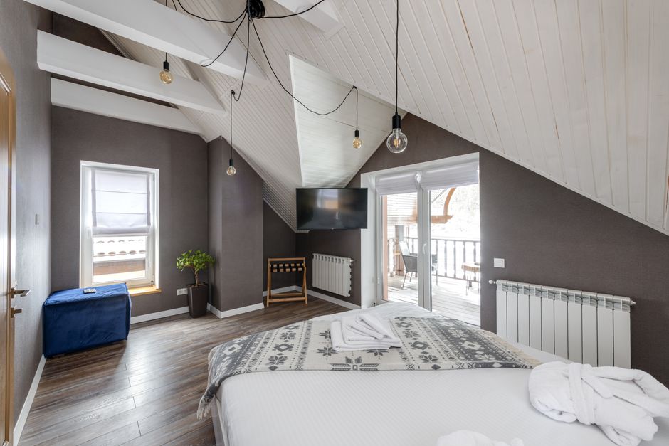 A modern bedroom with a large bed, balcony access, and stylish lighting.