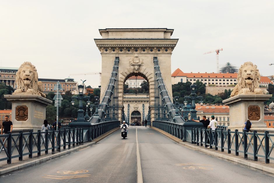 Iconic Széchenyi Chain Bridge in Budapest with tourists and lion sculptures on a clear day.