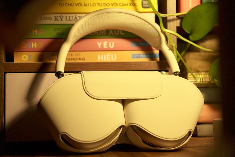 Stylish white headphones elegantly displayed on a wooden shelf with books and plants, creating a modern aesthetic.