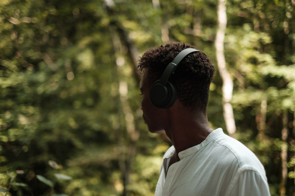 Anonymous African American male listening to music in modern headphones while looking away in park