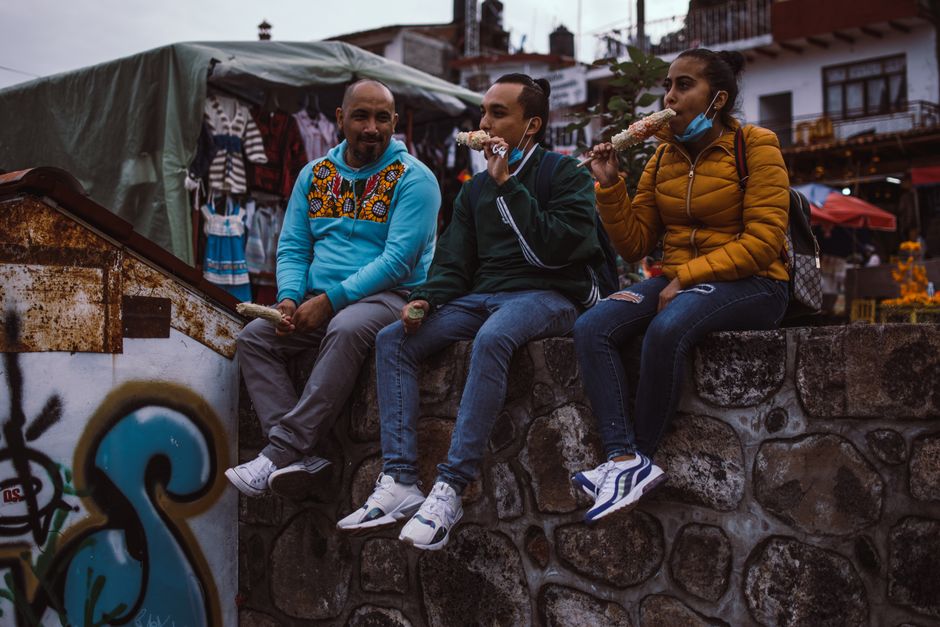 A candid capture of three people enjoying street food on a stone wall in Janitzio, Michoacán.