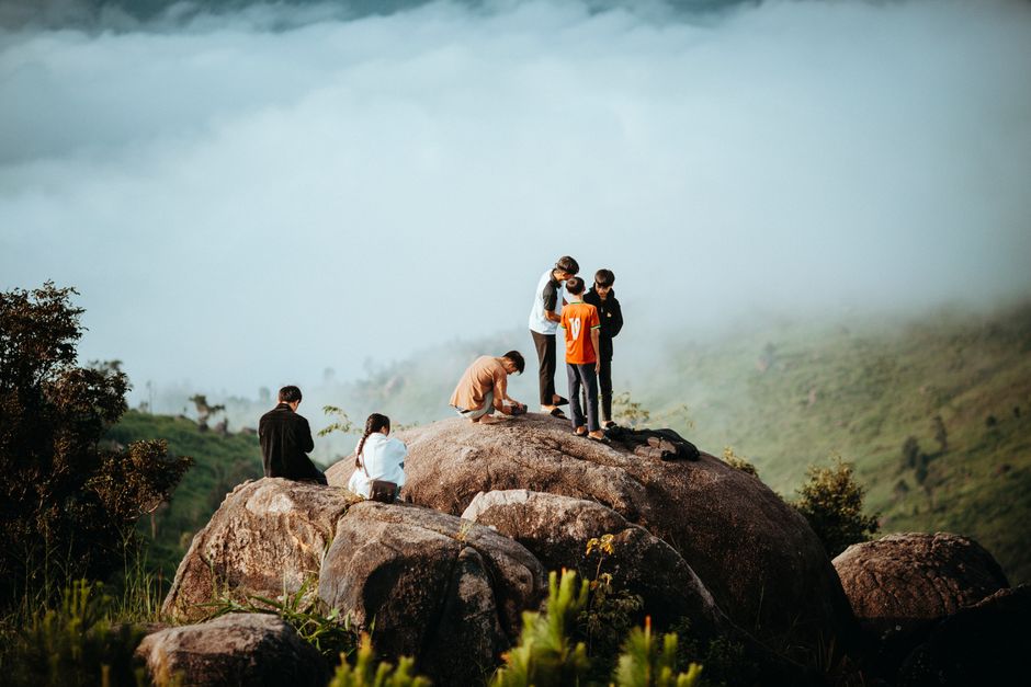 A group of teenagers hiking and exploring a rocky hilltop in Kon Tum, Vietnam.