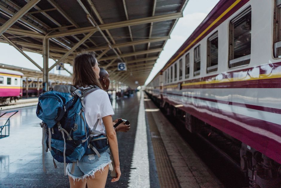 Two women with backpacks waiting at a railway station for a train. Travel and adventure theme.