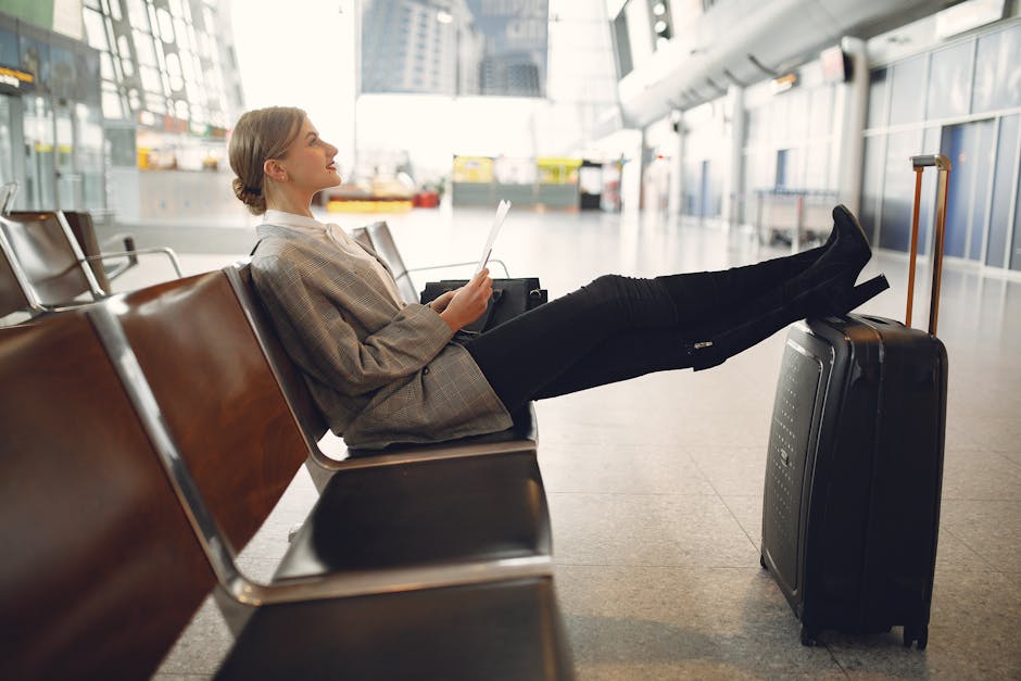 A woman relaxes in an airport terminal waiting area, reading a tablet with luggage nearby.