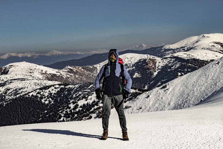 Trekker standing in snowy winter mountains